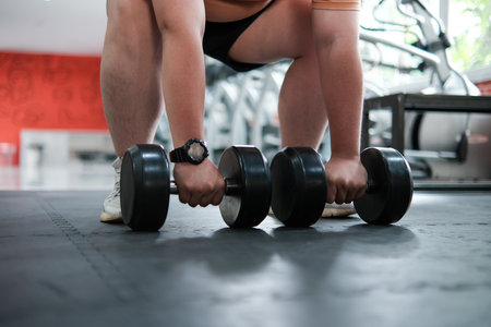 A man is lifting three dumbbells in a gymの写真素材