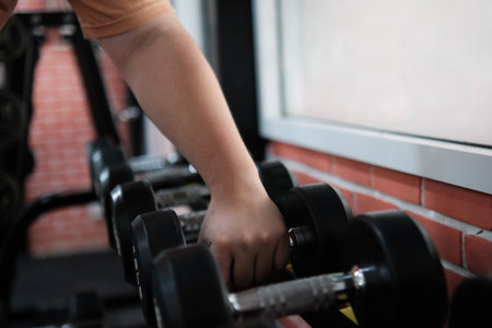 A person is holding a pair of dumbbells in a gymの写真素材