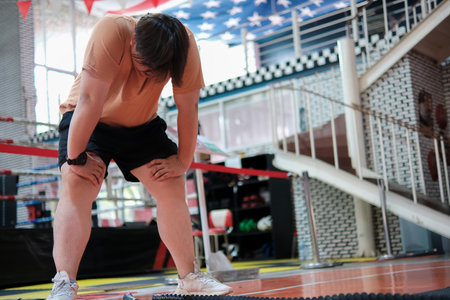 A man in a tan shirt is kneeling on the ground with his knees bent