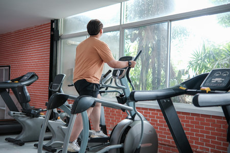 A man is on a stationary bike in a gym