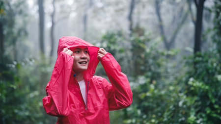 Smiling woman in red raincoat enjoying the forest