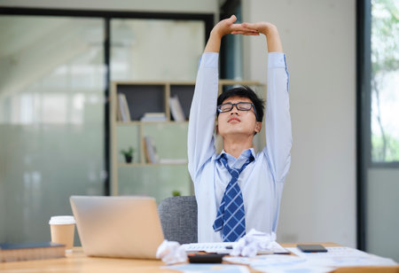 Businessman Stretching at Desk to Relieve Stress from Workの写真素材
