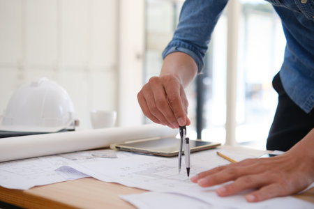 Architect designing house plans using a compass on a work desk in an office