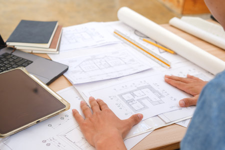 Architect and engineer analyzing blueprints at a work desk in an officeの写真素材