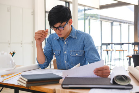 Architect and engineer analyzing blueprints at a work desk in an office