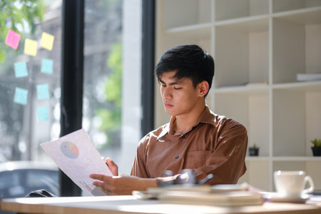 Young businessman analyzing financial data and market trends for investment decisionsの写真素材
