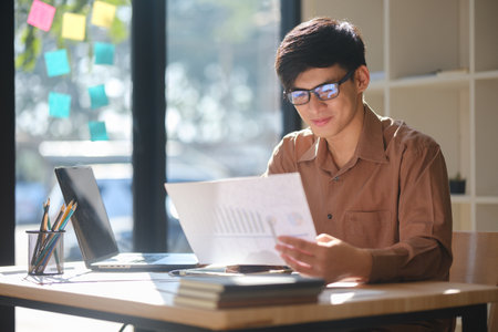 Young businessman analyzing financial data and market trends for investment decisionsの写真素材
