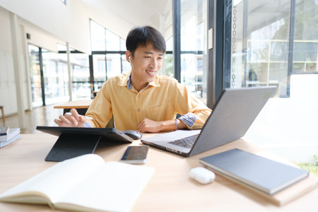 Student studying online and preparing for exams with digital devices and booksの写真素材