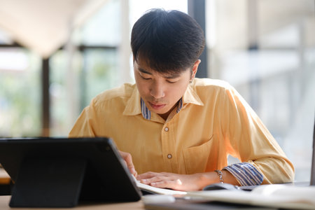 Student studying online and preparing for exams with digital devices and booksの写真素材