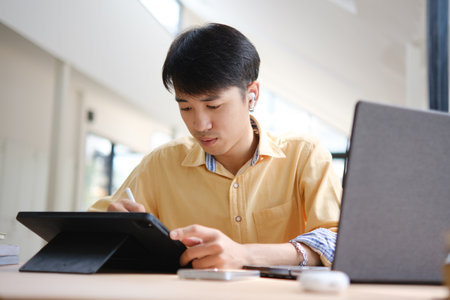 Student studying online and preparing for exams with digital devices and booksの写真素材