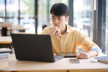 Student studying online and preparing for exams with digital devices and booksの写真素材