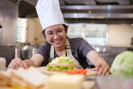 Focused chef carefully a gourmet sandwich in a professional kitchen with fresh ingredients in viewの写真素材