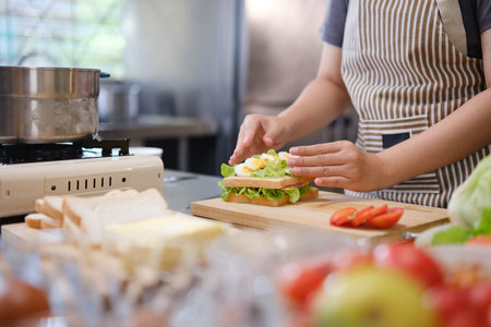 Focused chef carefully a gourmet sandwich in a professional kitchen with fresh ingredients in viewの写真素材