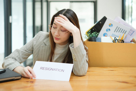 Unemployed woman with resignation letter and office box showing stress after layoffの写真素材