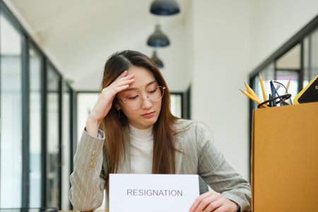 Unemployed woman with resignation letter and office box showing stress after layoffの写真素材