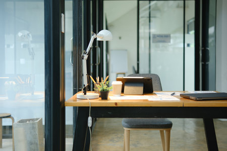 Modern office desk with tablet, financial documents, and coffee cup in a professional workspaceの写真素材
