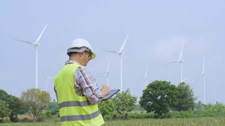 Engineer working with laptop at wind turbine field generating electricity for renewable clean energy.の写真素材