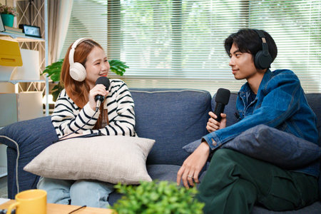 Two young people recording podcast at home with headphones and microphones