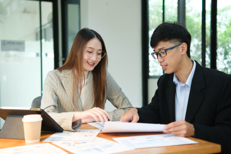 Two business people discuss financial strategy and collaborate with colleagues.の写真素材