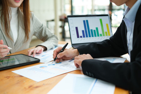 Two business people discuss financial strategy and collaborate with colleagues.の写真素材