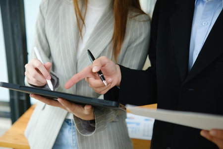 Two business people discuss financial strategy and collaborate with colleagues.の写真素材