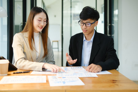 Two business people discuss financial strategy and collaborate with colleagues.の写真素材