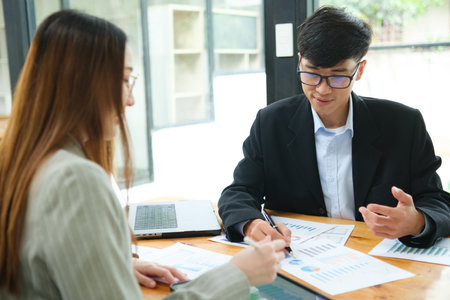 Two business people discuss financial strategy and collaborate with colleagues.の写真素材