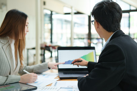 Two business people discuss financial strategy and collaborate with colleagues.の写真素材