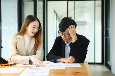 Two business people discuss financial strategy and collaborate with colleagues.の写真素材