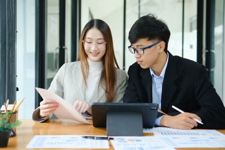 Two business people discuss financial strategy and collaborate with colleagues.の写真素材