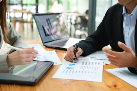 Two business people discuss financial strategy and collaborate with colleagues.の写真素材