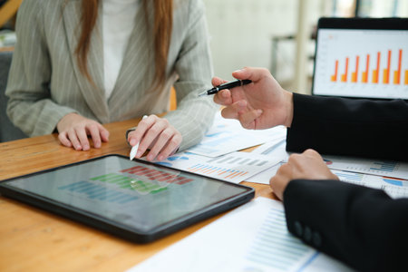 Two business people discuss financial strategy and collaborate with colleagues.の写真素材