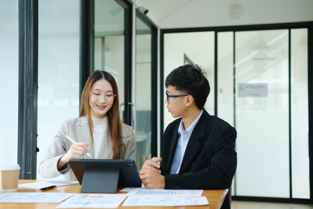 Two business people discuss financial strategy and collaborate with colleagues.の写真素材