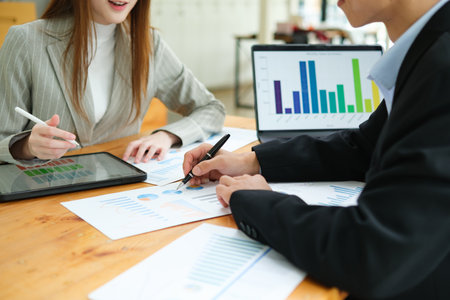 Two business people discuss financial strategy and collaborate with colleagues.の写真素材