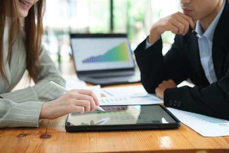 Two business people discuss financial strategy and collaborate with colleagues.の写真素材