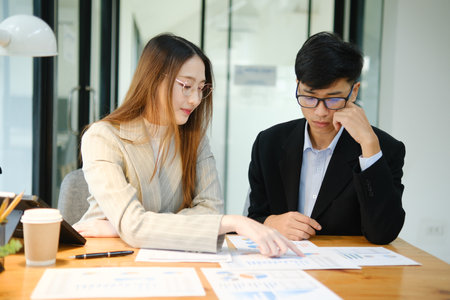 Two business people discuss financial strategy and collaborate with colleagues.の写真素材