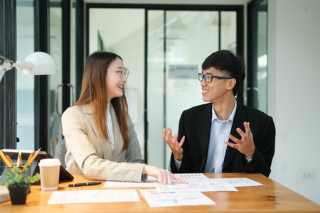 Two business people discuss financial strategy and collaborate with colleagues.の写真素材