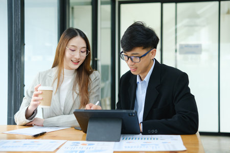 Two business people discuss financial strategy and collaborate with colleagues.の写真素材