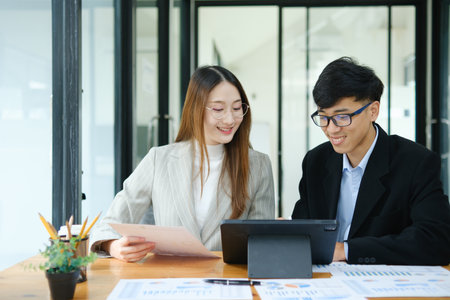 Two business people discuss financial strategy and collaborate with colleagues.の写真素材
