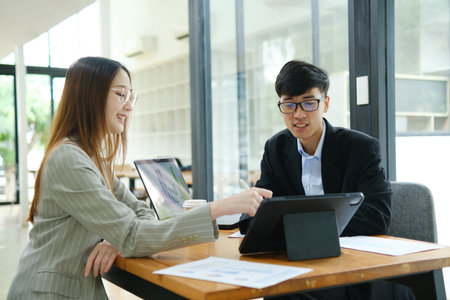 Two business people discuss financial strategy and collaborate with colleagues.の写真素材