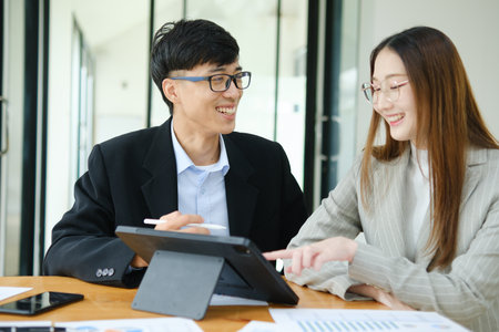 Two business people discuss financial strategy and collaborate with colleagues.の写真素材