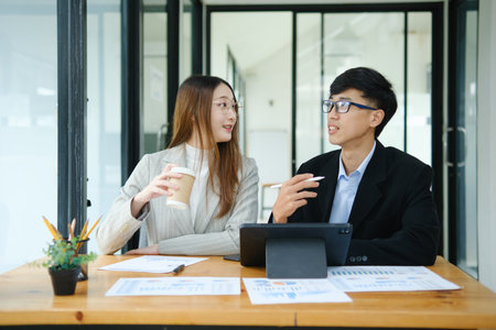 Two business people discuss financial strategy and collaborate with colleagues.の写真素材