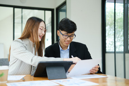 Two business people discuss financial strategy and collaborate with colleagues.の写真素材