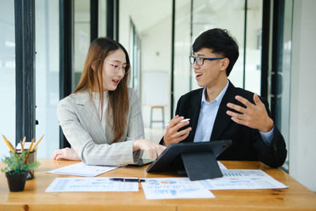 Two business people discuss financial strategy and collaborate with colleagues.の写真素材