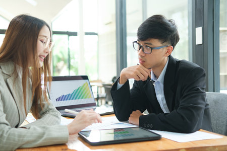 Two business people discuss financial strategy and collaborate with colleagues.の写真素材