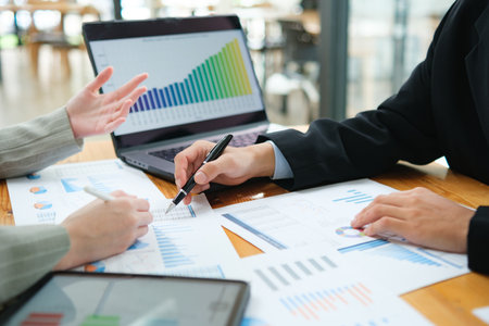Two business people discuss financial strategy and collaborate with colleagues.の写真素材