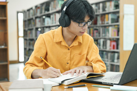 Young college student using computer and headphones studying online.の写真素材