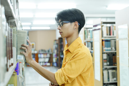 Man searching books in shelf at library.の写真素材