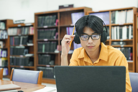 Young male student study in the school library using laptop and learning online.の写真素材