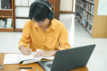 Young collage student using computer and mobile device studying online.の写真素材